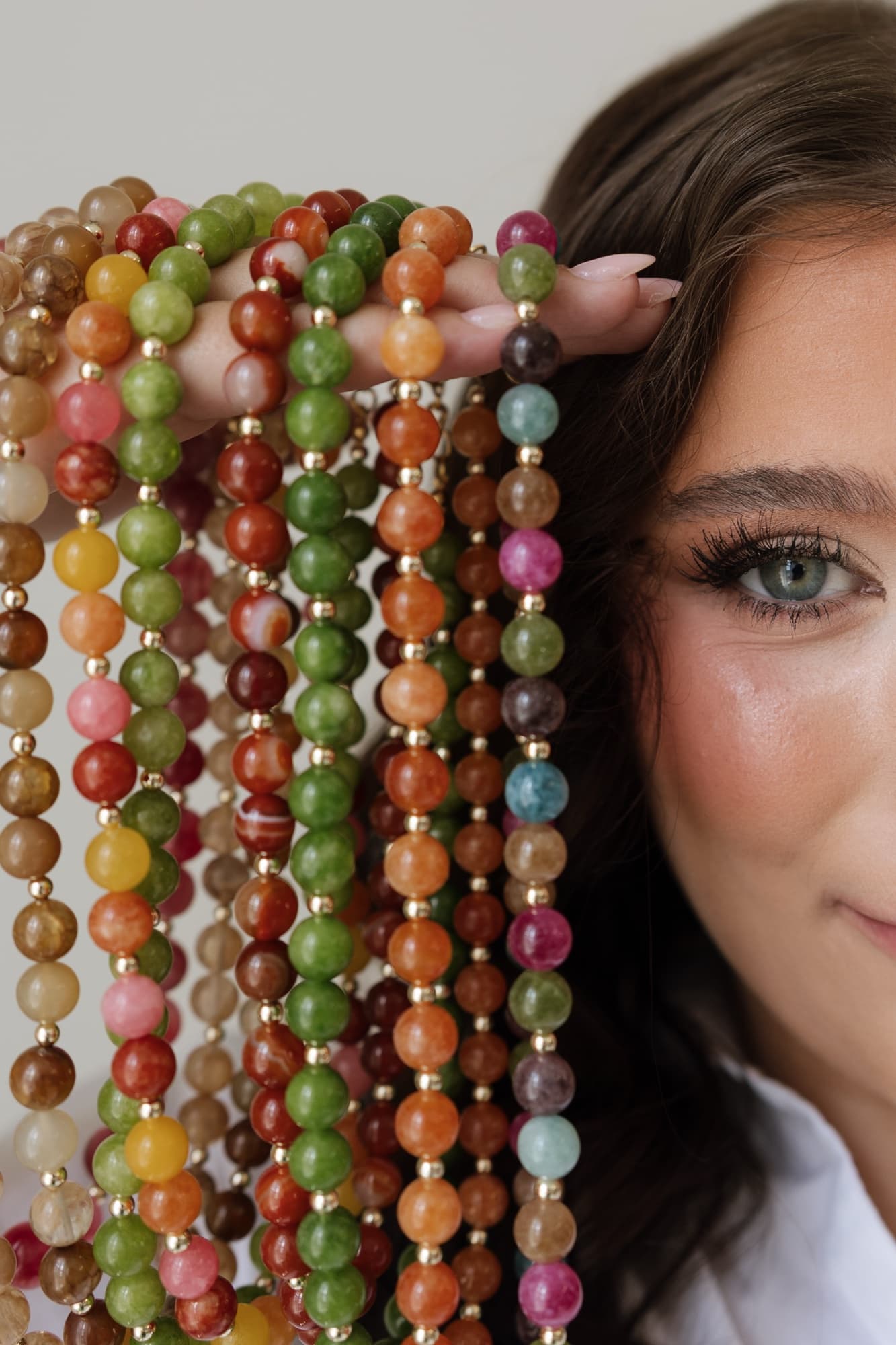 Taylor holding strands of colorful beaded necklaces beside her face